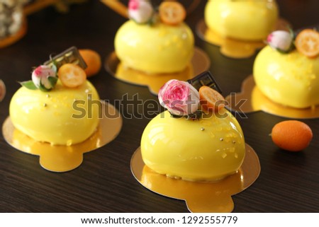 Homemade bright mousse cakes "Hearts" with yellow mirror coating on a dark background
