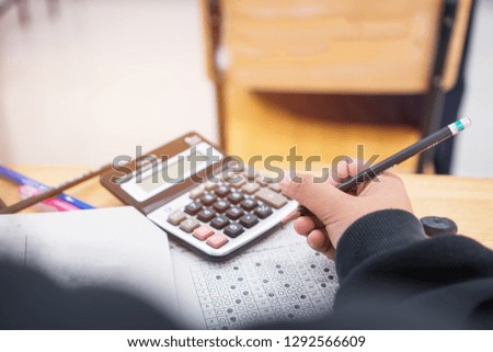 School / university Students hands taking exams, writing examination room with calculator holding pencil on optical form answers paper on doing final test in classroom. Education assessment Concept