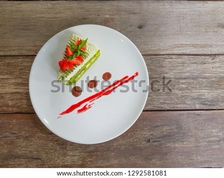 A piece of green tea cake on a white plate and brown wood background. Top view picture concept