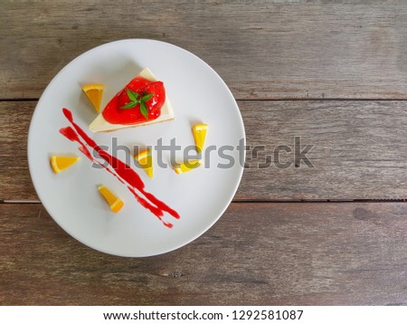 A piece of strawberry cheesecake cake on a white plate and brown wood background. Top view picture concept