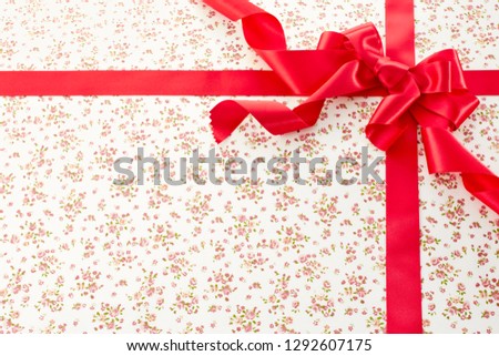 Shiny red satin ribbon on flower pattern background 