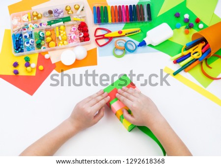 Child makes a hack box chameleon. Material for creativity on a white background. Baby hand. Rainbow colored paper.