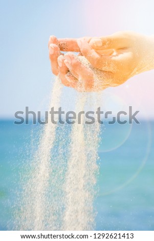 hands are pouring sand by the sea