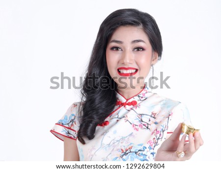 Gold ingot in Beautiful smiling Chinese woman's hands. Happy asian girl holding gold ingot present of Chinese New Year. given during holidays or special occasions.