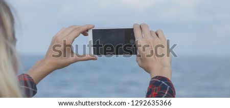 beautiful girl takes pictures of the sea. Women's hands, holding the smartphone