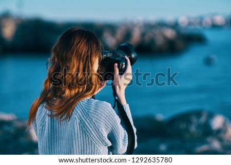 Photographer with a camera in hand on the nature near the sea in the mountains                      