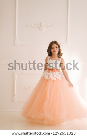 Happy little princess in beautiful dress walk though the big studio
