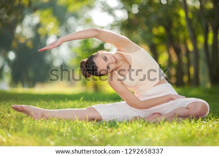 Yoga outdoor. Happy woman doing yoga exercises, meditate in the park. Yoga meditation in nature. Concept of healthy lifestyle and relaxation. Pretty woman practicing yoga on the grass