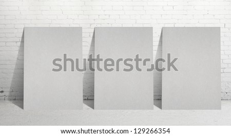 three paper poster and  brick wall