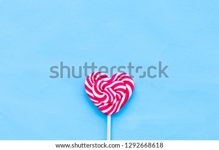 Single Valentines Day heart-shaped lollipop blue background. Love concept. Minimalism.