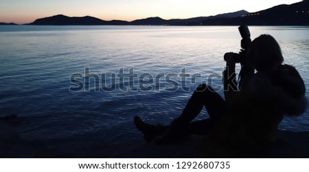 Silhouette of photographer taking photos of sea horizon during sunset.