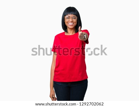 Beautiful young african american woman wearing glasses over isolated background smiling friendly offering handshake as greeting and welcoming. Successful business.