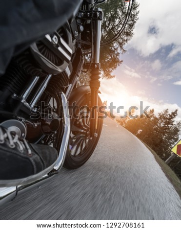 Detail of motorcycle rider driving in Alpine road.