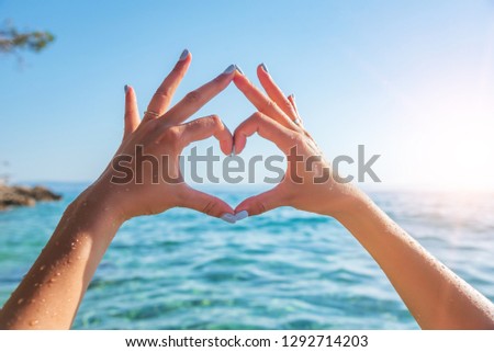 Woman making heart shape against the sea in summer