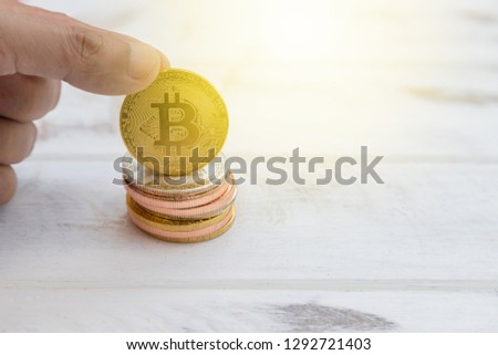 Golden bitcoin facing with stack on white wood background