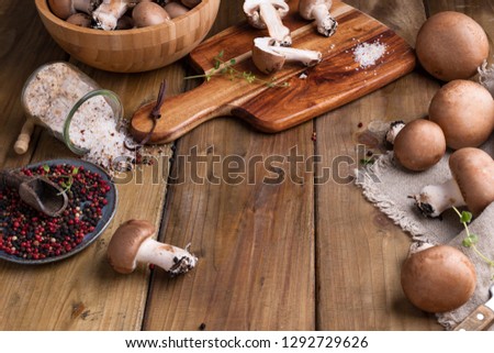 Champignon mushrooms with red onions and spices on a wooden background, wooden utensils. Rustic style photo. Vegetarian lunch of vegetables. Place for text
