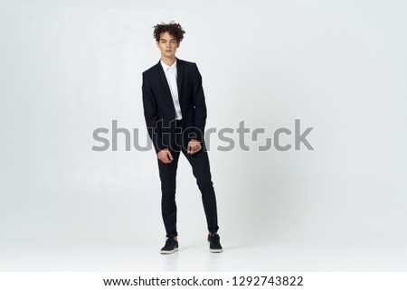 Handsome business man in a dark suit with curly hair in full growth on a gray background