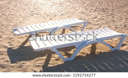 Two sunlongers on the sand beach in summer. Royalty-Free Stock Photo #1292754277