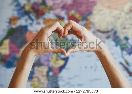 female hands in form of heart against world map background 