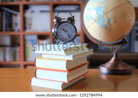Close-up of several books stacked on a table in a library the globe is the background selective focus and shallow depth of field
