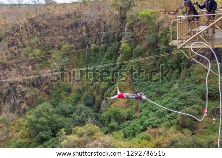A teenage girl bungee jumping off the Victoria Falls Bridge in Zambia/Zimbabwe Royalty-Free Stock Photo #1292786515