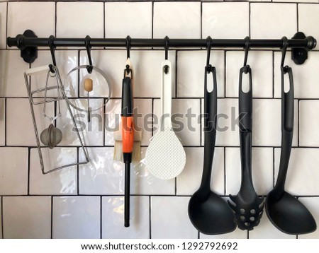 White ceramic tile wall of modern kitchen with kitchen equipment hanging rail.
