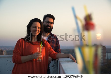Man and women smiling and looking at the camera with cocktail in first plan - Image