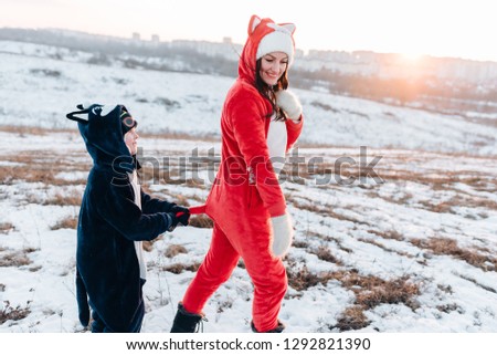 Happy mother and son in animal  pajamas playing having fun together at 
 winter sunny day.  Family enjoying winter. Winter lifestyle concept.  