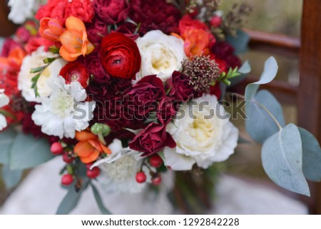 bright autumn wedding bridal bouquet, standing on a chair in the woods. floral arrangement of flowers to celebrate the holiday decor