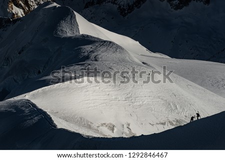 Free ride skiers, skiing down steep slope, good background with white valley and mountains in french alps. Winter sport concept with adventure guys on mountain top hiking to start point.