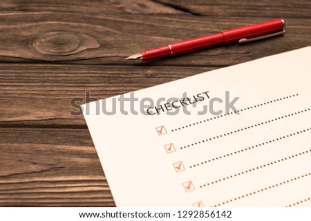 checklist, fountain pen on wooden background. business planning.