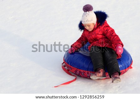 girl on an inflatable sled rides from a snowy slope