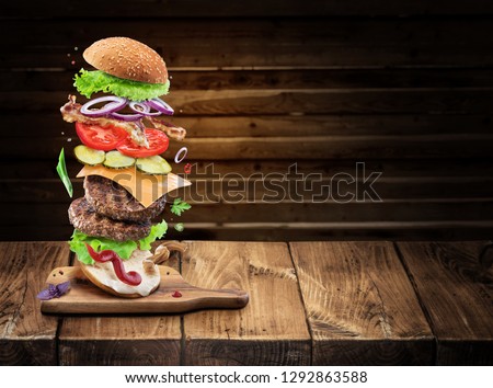 Hamburger ingredients falling down one by one to create a perfect meal. Colorful conceptual picture of burger cooking.