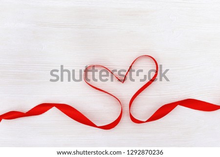 Shape of heart from red ribbon on white wood background. Happy Saint Valentin day. Mother Womens Day concept. Copy space for text. 
