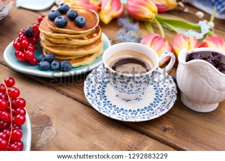 Fresh aromatic coffee in a vintage cup, homemade pastries for breakfast with blueberries and currants, on a wooden background and spring tulips. Free space for text