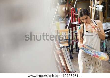 Professional Woman artist painting picture in art studio.