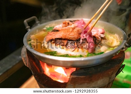 the pan for Thai Barbecue or Moo Kra Ta with raw pork and chopsticks, on top of Thai traditional stove. Royalty-Free Stock Photo #1292928355