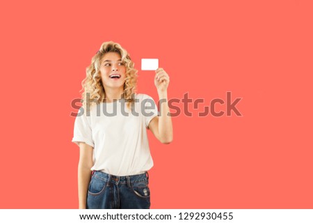 
Emotional young very beautiful girl holding a business card on an isolated background in the studio. Fashion and communication concept
