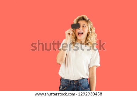
Emotional young very beautiful girl holding a business card on an isolated background in the studio. Fashion and communication concept