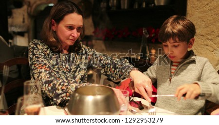 Mom and child eating fondue for supper, Candid authentic scene of family eating traditional swiss cuisine, fondue