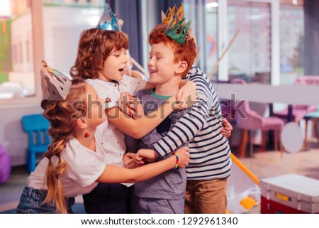 My cousin. Cheerful red-haired kid embracing his friend while laughing at joke