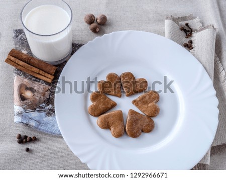 The glass of the milk with handmade's cakes on the plate near serviettes with  allspices and other spices on the natural tablecloth This picture have made by middleformat camera