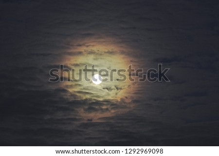 Full moon with altocumulus clouds and colorful corona, also called aureole (optical phenomenon).