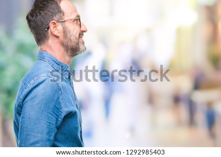 Middle age hoary senior man wearing glasses over isolated background looking to side, relax profile pose with natural face with confident smile.