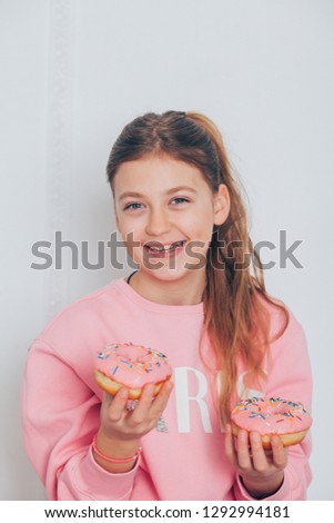 Stylish girl with, holding fresh pink donuts with powder ready to enjoy sweets. Portrait of attractive young woman in having fun with sweet-stuff