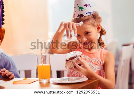 Soft cream. Cheerful little female keeping smile on her face while going to eat cake