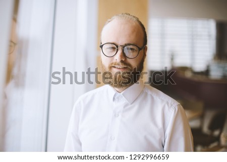 Close up portrait of young bearded man in casual wearing glasses and looking at the camera