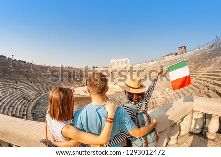 Group of Happy friends tourists with italian flag admiring view of the Verona amphitheater arena