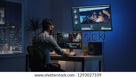 Medium shot of a young man sitting back and editing a video inside a modern video studio Royalty-Free Stock Photo #1293027109