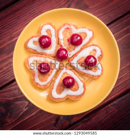 A flower laid out of heart-shaped cookies with frozen cherries on top